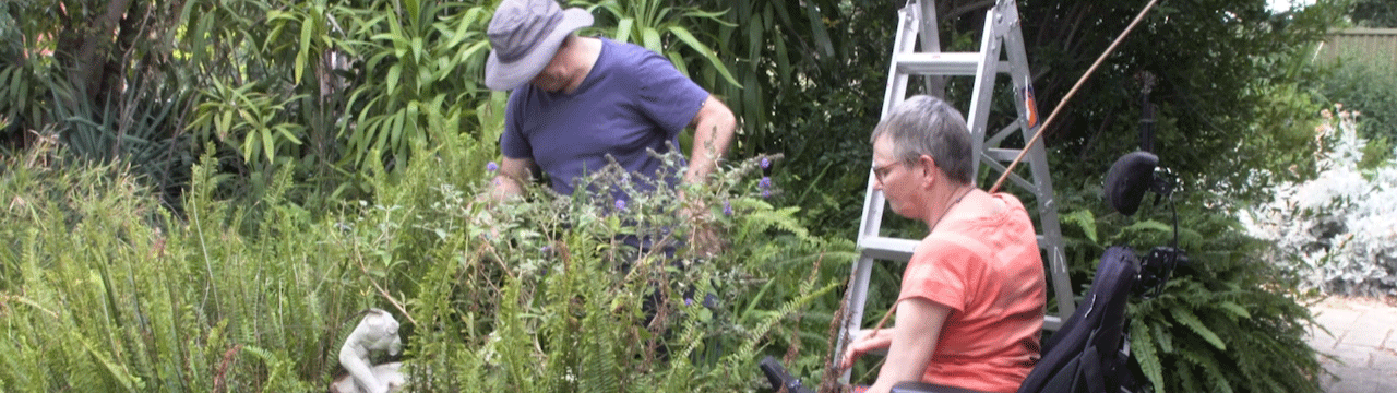 A woman works in the garden with her support worker